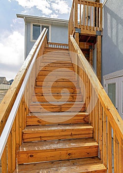 Vertical Close up of wooden stairway with handrails at home exterior against cloudy sky