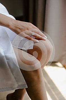 Vertical closeup of the bride sitting on a chair in a robe