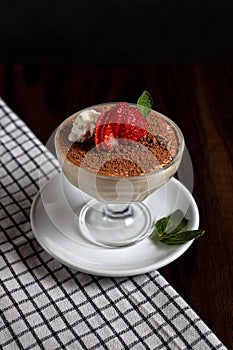 Vertical closeup of a creamy dessert in a glass with a strawberry and mint on top
