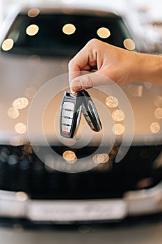 Vertical closeup cropped shot of unrecognizable buyer male holding in hand car key from new auto after buying at