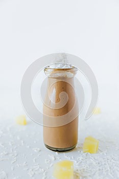 Vertical closeup of a glass of chocolate milkshake on a table, with cream on top