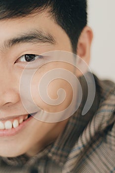 Vertical closeup half face portrait of an Asian cute friendly man smiling happily