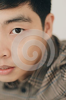 Vertical closeup half face portrait of an Asian handsome man with a serious facial expression