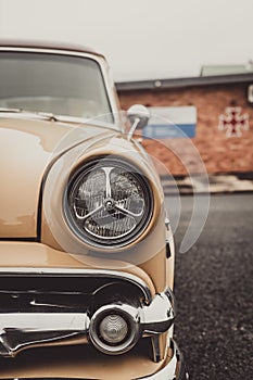 Vertical closeup of headlights on a vintage car
