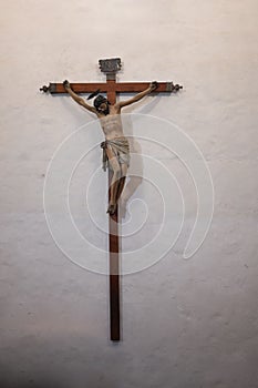 Vertical closeup of Jesus Christ nailed to the wooden cross hanging on the wall