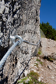 Vertical closeup of metal attachments and cables on a mountainside for hiker safety