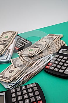 Vertical closeup of a pack of dollars black calculators around on the green background