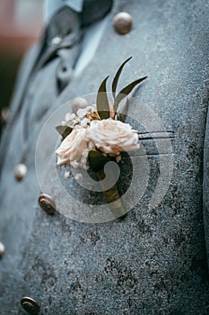 Vertical closeup of a pink buttonhole on the groom's suit