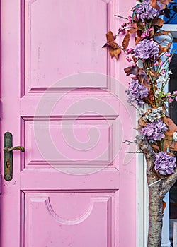 Vertical closeup of a pink wooden door decorated with flowers