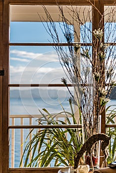 Vertical closeup of rain deer made of wire by a beach house window seascape blurred background