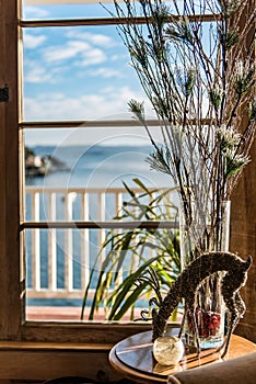 Vertical closeup of rain deer made of wire by a beach house window seascape blurred background