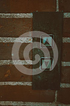 Vertical closeup of a rusty elevator dispatching control system with marks up and down on the wall