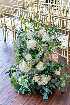 Vertical closeup shot of a beautiful floral composition next to the chairs in the wedding venue