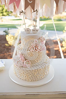 Vertical closeup shot of a beautiful wedding cake in pastel tones decorated with flowers on table