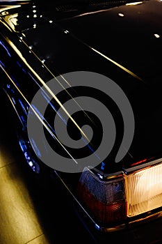 Vertical closeup shot of a black luxurious shiny vehicle parked on the street during nighttime