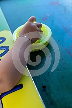 Vertical closeup shot of a child's hand holding a striker for an air hockey game