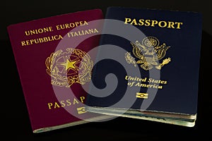 Vertical closeup shot of a dark blue US passport and red Italian passport on a black background