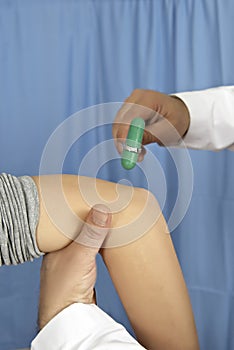 Vertical closeup shot of a doctor checking a patient elbow with a reflex hammer