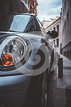 Vertical closeup shot of a gray car parked on the street at daytime