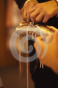 Vertical closeup shot of a groom tying rings onto a pillow at a wedding