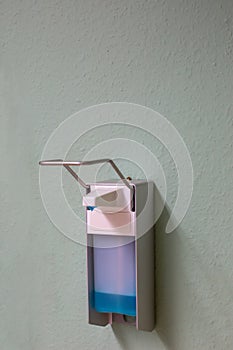 Vertical closeup shot of a hand sanitizer dispenser attached to a wall