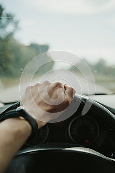 Vertical closeup shot of a hand on a steering wheel