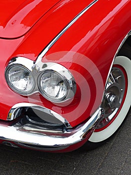 Vertical closeup shot of headlights of a red vintage car