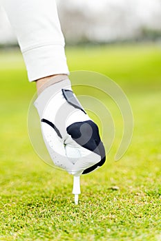 Vertical closeup shot of a man putting a golf ball in a field