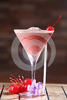 Vertical closeup shot of a martini glass with a maraschino cherry cocktail