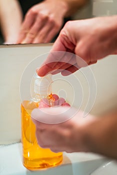 Vertical closeup shot of a person pouring soap into the hands
