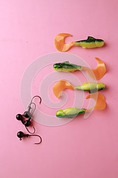 Vertical closeup shot of plastic fishing lures on a pink background