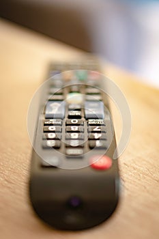 Vertical closeup shot of a remote controller on a wooden surface with a blurred background