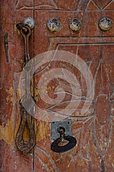 Vertical closeup shot of the rusty door handle and the door lock  with the key installed in it