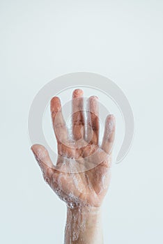 Vertical closeup shot of the soaped hand of a person