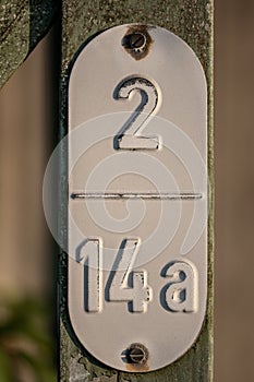 Vertical closeup shot of a weathered metal railway sign with a number 2/14a