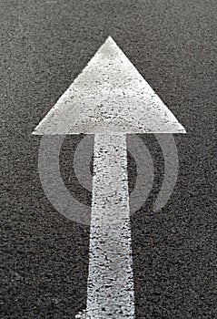 Vertical closeup shot of a white arrow on asphalt of a road traffic signal
