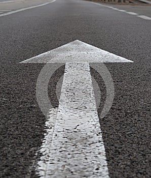 Vertical closeup shot of a white arrow on asphalt of a road traffic signal