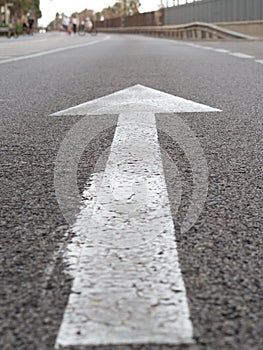 Vertical closeup shot of a white arrow on asphalt of a road traffic signal