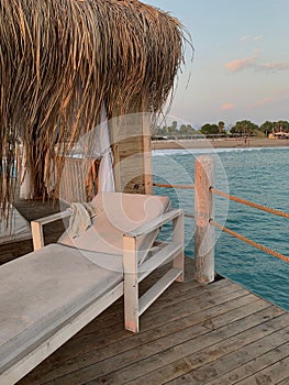 Vertical closeup shot of a white sunlounge on a wooden surface over the ocean