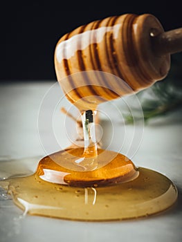 Vertical closeup shot of a wood dipper of honey and honey itself leaking from it