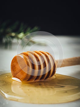 Vertical closeup shot of a wood dipper of honey and honey leaking from it