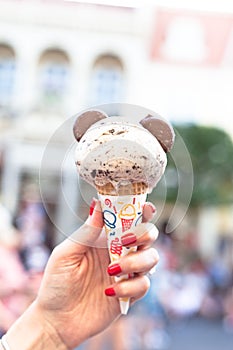 Vertical closeup shot of a woomen holding an ice cream cone with Micky mouse ears