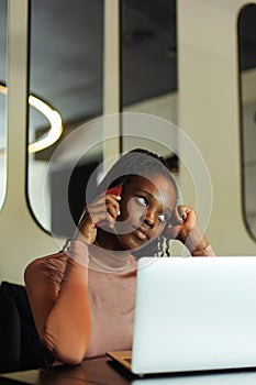 Vertical closeup unhappy multiethnic business woman talk phone. Bad news. Remote working on laptop in cafe, e-commerce