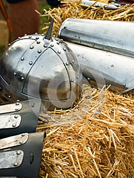 Vertical closeup of a Viking helmet and armors on the crafted paddy straw, blurred background