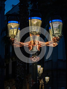 Vertical closeup of a vintage illuminated street light in the dark photo