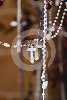 Vertical closeup of white Catholic rosary beads hanging from tree branches in Santa Fe, New Mexico