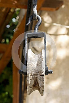 Vertical closeup wooden pulley with a rustic hook on top