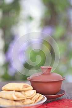 Vertical composition: a plate of spring rolls, a cup of tea and a red envelope.The Chinese character in the picture means `happine