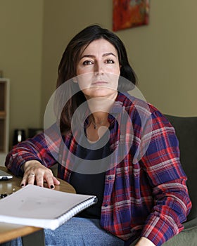 Vertical confident, powerful smiling dark-haired woman looking at camera, sit at office desk with paper report documents