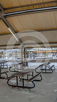 Vertical Covered picnic area and playground at a park blanketed with snow in winter